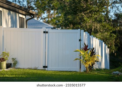 White vinyl picket fence on green lawn surrounding property grounds for backyard protection and privacy - Shutterstock ID 2335015577