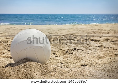 White volleyball sits on top of the sand. 