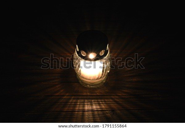 White votive candle on\
dark background