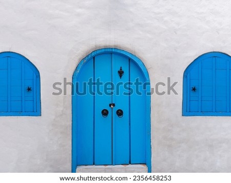 White wall with an arch old light blue traditional door and windows made from woods. Santorini architecture style.