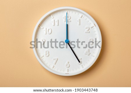white wall clock with blue second hand show five o'clock