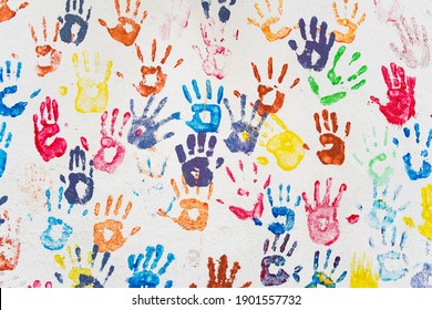 White wall with colorful multicolored hand prints. Friendship concept background. Children hand prints on the wall - Powered by Shutterstock