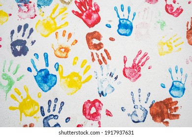 White wall with colorful multicolored hand prints. Friendship concept background. Children hand prints on the wall - Powered by Shutterstock