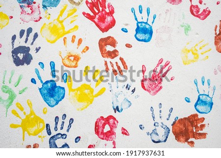 White wall with colorful multicolored hand prints. Friendship concept background. Children hand prints on the wall