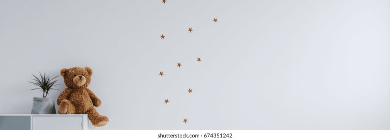 White wall with golden stars stickers in baby's room interior
