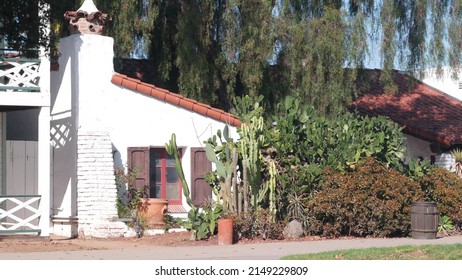 White wall of mexican old village house, wooden window with shutters, garden from succulent plants and tall cactus. Suburban countryside rural exterior, rustic provincial ranch, homestead architecture