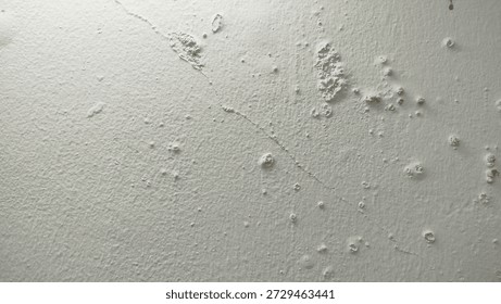 White wall paint background grumbling because it's been too long. Close up background of a white concrete cement wall that is cracked and the paint is peeling off. Old wall background wall with peelin