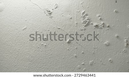 White wall paint background grumbling because it's been too long. Close up background of a white concrete cement wall that is cracked and the paint is peeling off. Old wall background wall with peelin