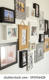 White Wall With Photos Of The Family In Various Photo Frames