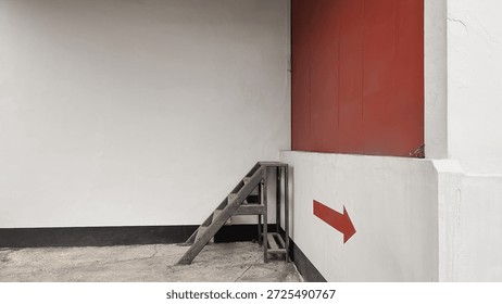 white wall with a red panel, small metal stairs, and a bold red right-pointing arrow on the lower wall, clean geometric composition, copy space on the left, modern urban architecture, direction and navigation concept.