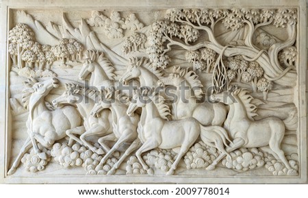 White wall sculpture depicting galloping horse.