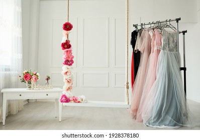 
White Wardrobe, Large White Strap, Beautiful Dresses In Pastel Colors Hang On The Hanger. Next To It, A Rope Entwined With Beautiful, Intense Flowers.