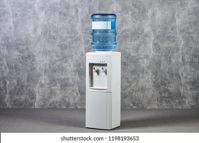 White water cooler gallon in office against gray textured wall background. International Exhibition furniture elements in large warehouse interior. - Shutterstock ID 1198193653