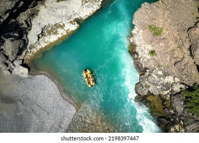 White Water Rafting.  Adventure And Sport. A Yellow Raft Floating Among The Rocks On The Crystal Clear, Blue-green Water. Perpendicular Drone View Of The Rafters Floating On Vjose River, Albania. 