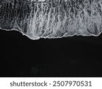 White waves on a black sand beach in a volcanic island in Iceland from a drone view