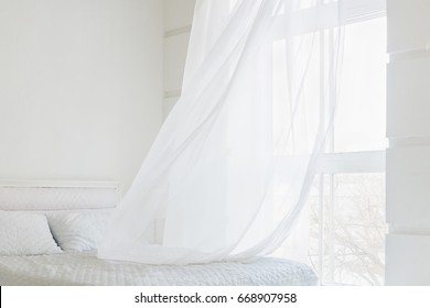 White waving curtain in white bedroom with window
