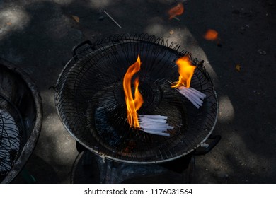 White Wax Candles With Orange Fire In Metallic Bowl. Religious Symbol Burning Candle. White Candle Flame In Metallic Bowl. Christian Church Ritual In Memoriam. Candle Flame Closeup On Dark Background