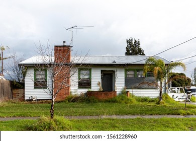 White weatherboard house abandoned in Australian suburbs.