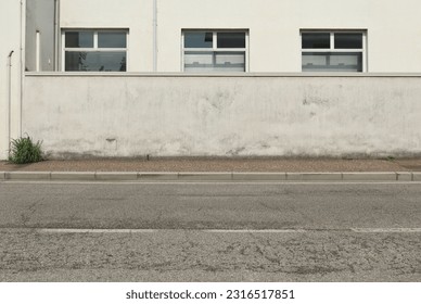 White weathered surrounding wall with white building on behind. Sidewalk and asphalt road in front, Background for copy space.