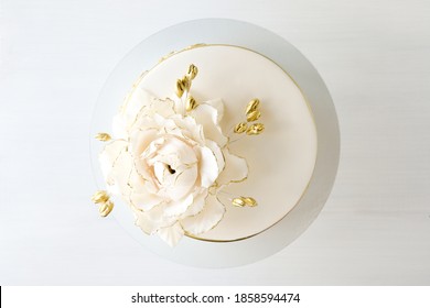 White Wedding Cake Decorated With Gold Flowers On A White Background. Top View.