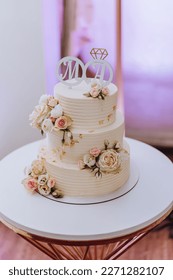 Torta de boda blanca con flores y arándanos. Bonita torta casera de tres niveles decorada con rosas rosas rosas rosas en un estilo rústico sobre una mesa de madera