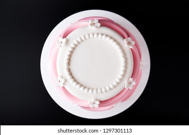 White Wedding Cake With Pink Elements Made From Pastry Mastic On A Black Background. Top View. Sugar Flowers, Marzipan Flowers And Mastic, Beautiful Decor For Decorating Cakes. Close-up.