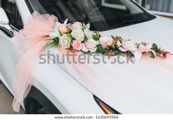 White wedding car decorated with roses\
flowers and pink bow. Wedding\
decorations.
