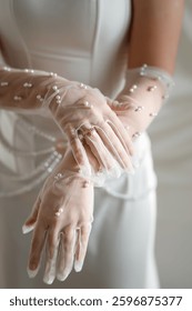 White wedding gloves of the bride decorated with pearls. Beautiful bride in white wedding dress and gloves, close-up