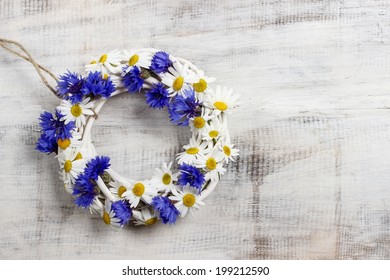 White wicker wreath decorated with cornflowers and chamomiles - Powered by Shutterstock