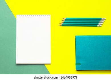 White wideopen blank clean notepad page and green pencils on yellow-green table.
