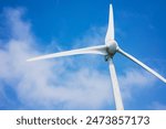 White wind turbine generating electricity on blue sky