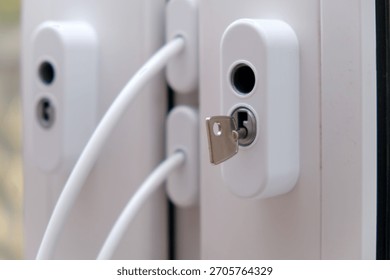 White window handle with key inserted into lock. Security and safety concept for home or office. Modern PVC window frame detail.