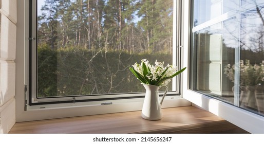 White window with mosuito net in a rustic wooden house overlooking the blossom garden.