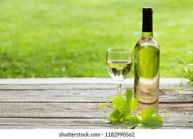 White Wine Bottle And Glass On Wooden Table. Outdoor Still Life. With Space For Your Text