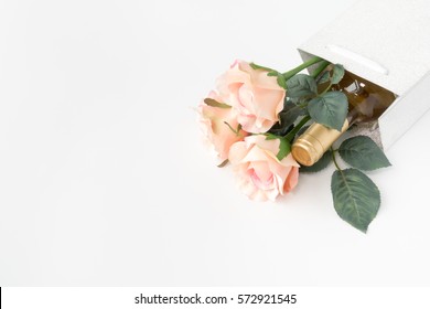 White Wine Bottle And Three Pink Roses In A Silver Glitter Gift Bag On White Background With Lots Of Copy Space.