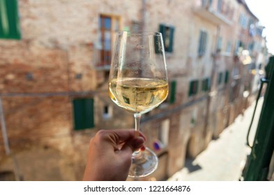 White wine glass in hand of italian person, living in historical Siena city, Tuscany. Leisure in Italy.