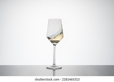 White Wine Movement Inside A Crystal Glass. White Wine Glass On White Background With Reflection On The Base. Image For Cutout.