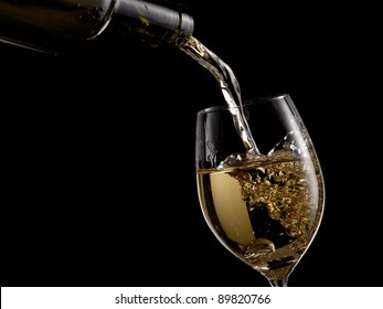 White Wine Pouring Into A Glass On Black Background