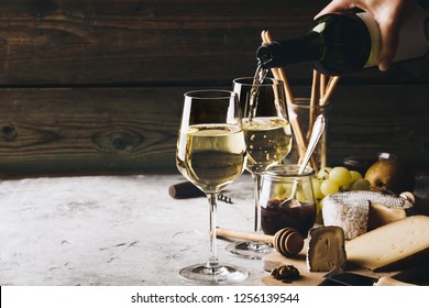 White wine pouring into glasses with charcuterie assortment on t