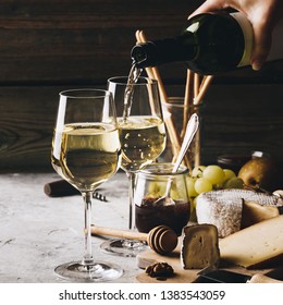 White wine pouring into glasses with charcuterie assortment - Powered by Shutterstock