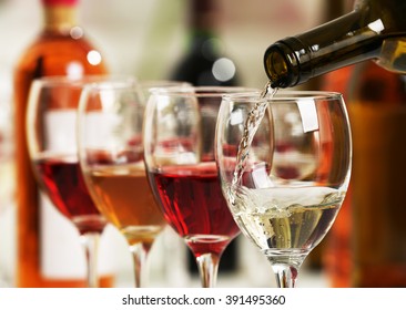 White wine pouring into glasses, closeup - Shutterstock ID 391495360