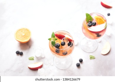 White Wine Sangria drink with Fruits and Blueberries on white marble, copy space. Glass of cold summer iced white sangria cocktail. - Powered by Shutterstock