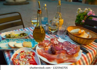 White Wine And Tasty Italian Homemade Snack. Italian Dinner Table With Homemade Antipasti, Cheese And Ham, Pienza, Tuscany, Italy