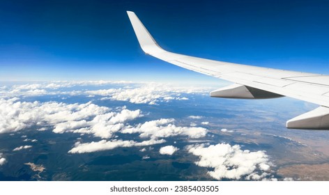 White wing from airplane window with mountain range below on sunny day. Great views of desert landscape and snowed peaks from plane - Powered by Shutterstock