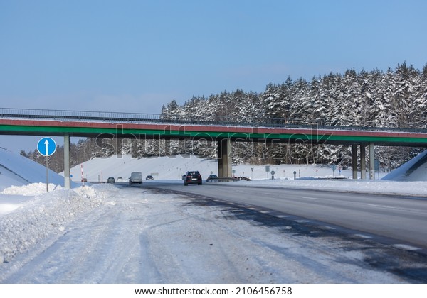 White winter landscape, gray asphalt road and\
transport bridge in the\
snow