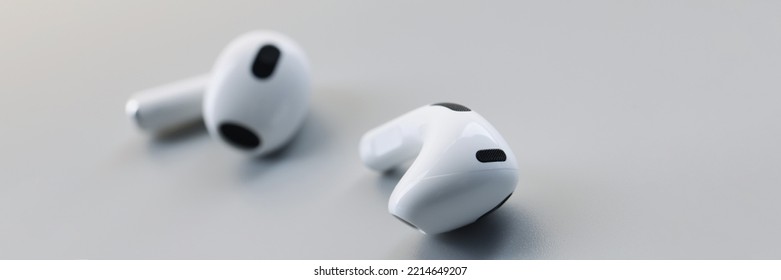 White Wireless Bluetooth Earbuds On A Gray Background