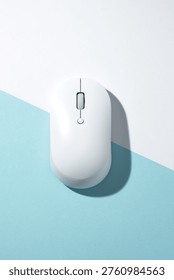 A white wireless computer mouse on a bisected light blue and white background. Top view, flat lay.