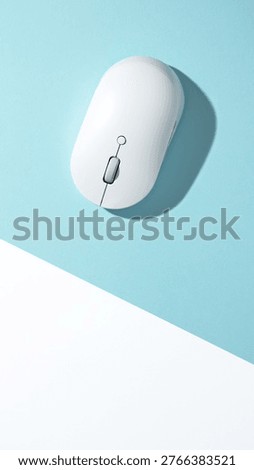 A white wireless computer mouse on a bisected light blue and white background. Top view, flat lay.