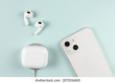 White wireless headphones on background. White Phone Dual Camera. wireless charging headphone