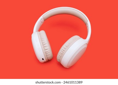 White wireless headphones on a bright orange background. Single wireless headphones for gaming and listening to music tracks. Wireless Over-Ear Headphones with clipping path. Music concept